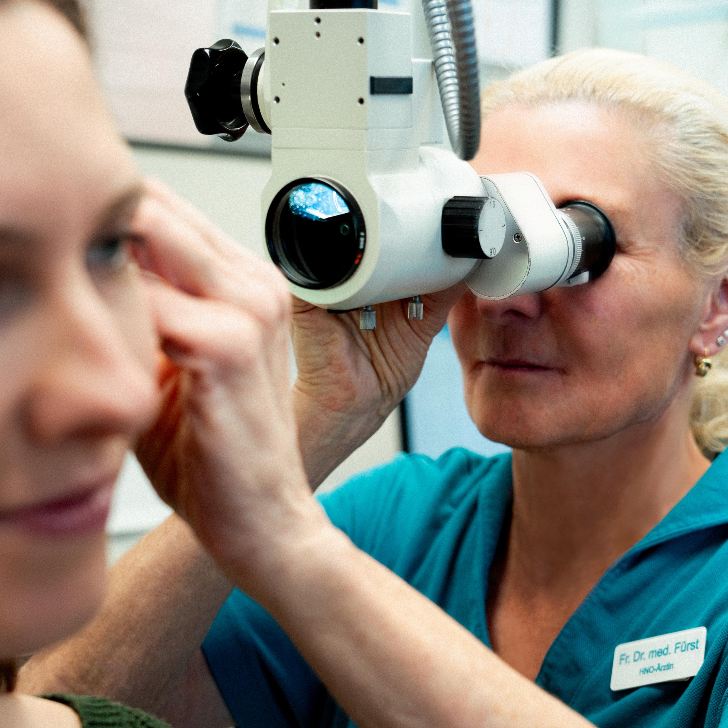 HNO-Ärztin Dr. med. Gudrun Fürst untersucht ein Ohr mit dem Mikroskop
